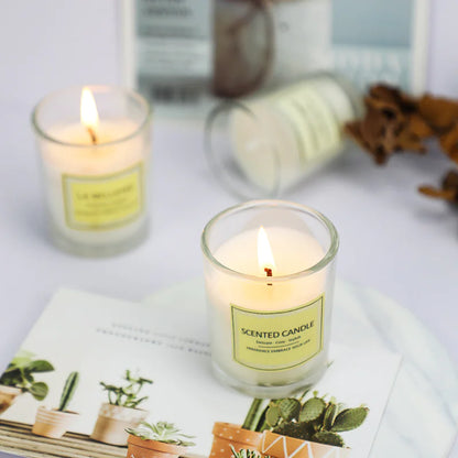 Two lit scented candles on a magazine with a blurred background