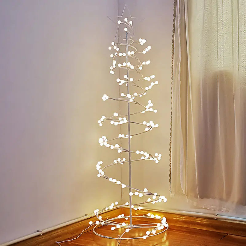 Decorative LED tree with lights on a wooden floor against a white wall.