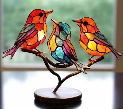 Colorful stained glass birds on a branch with a blurred background