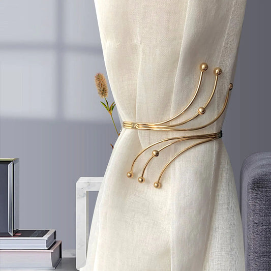 Gold curtain tieback on a white curtain with a blurred room background