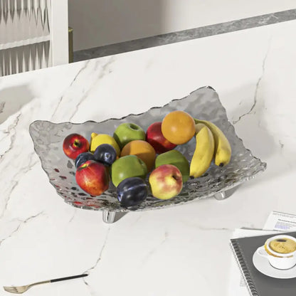 Fruit bowl with apples, bananas, and oranges on a marble countertop.