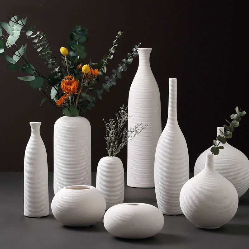 Collection of white ceramic vases on a dark background