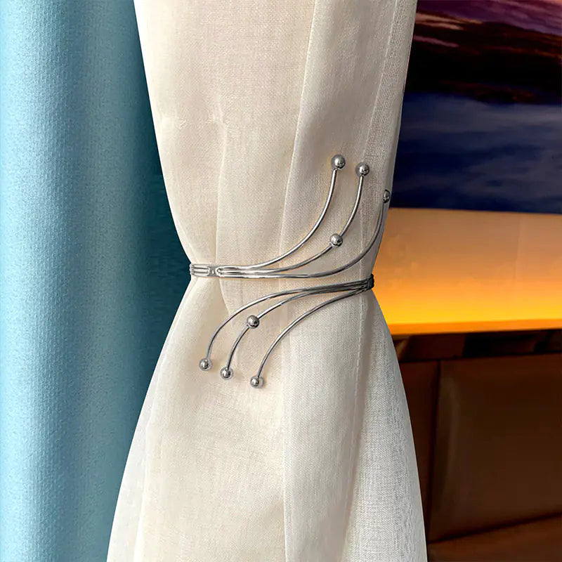 Beige curtain with decorative metal tieback against a blurred indoor background