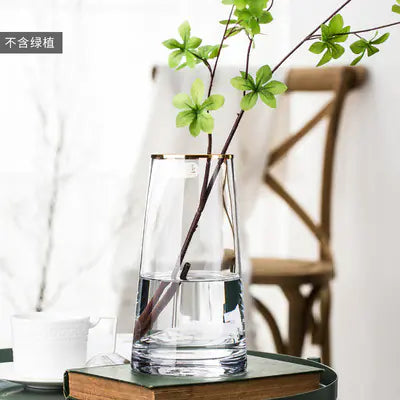 Clear glass vase with water and a branch on a table with a blurred background