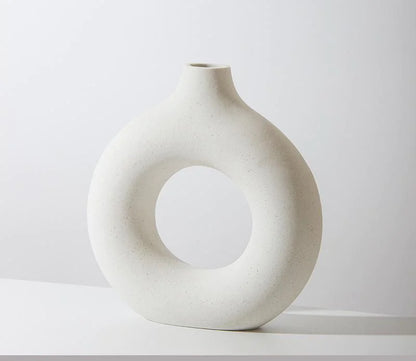 White ceramic vase with circular design on a white background