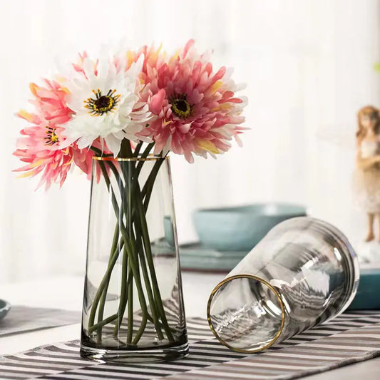 Clear glass vase with pink and white flowers on a striped surface