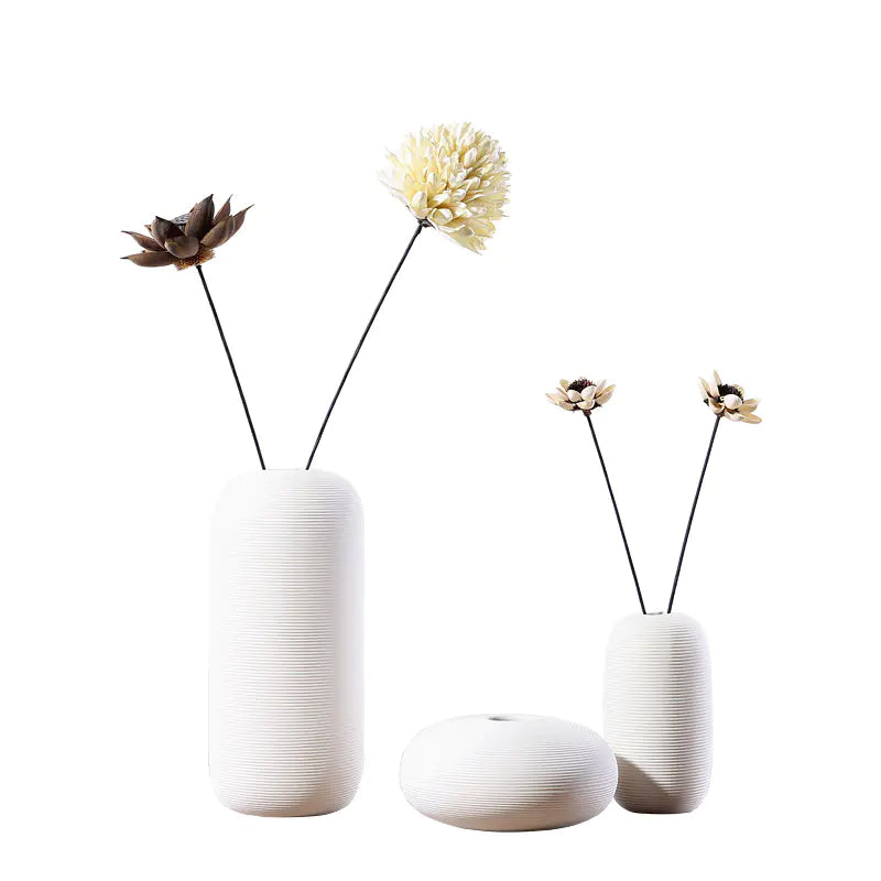 Set of three white textured vases with dried flowers on a white background