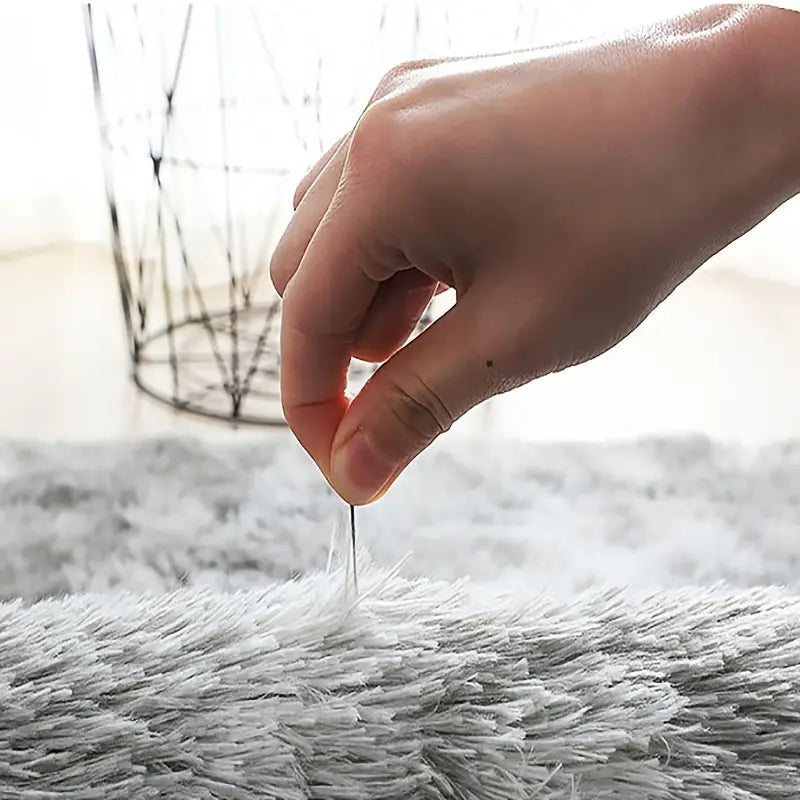 Hand holding a strand of gray fur fabric with a blurred background