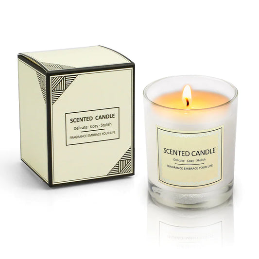 Scented candle with a lit flame next to its packaging on a white background