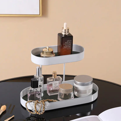 Two-tiered white tray with various items including bottles and a bowl on a black surface.