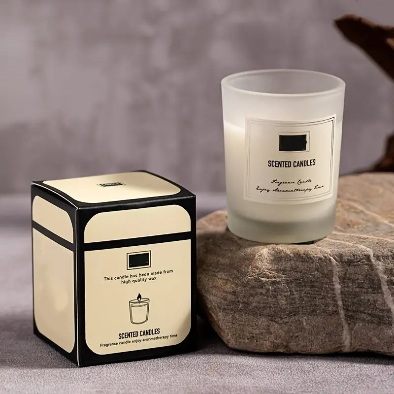 Scented candle and its packaging on a stone surface with a neutral background