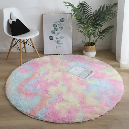 Round pastel tie-dye rug on a wooden floor with a chair, plant, and artwork in the background.