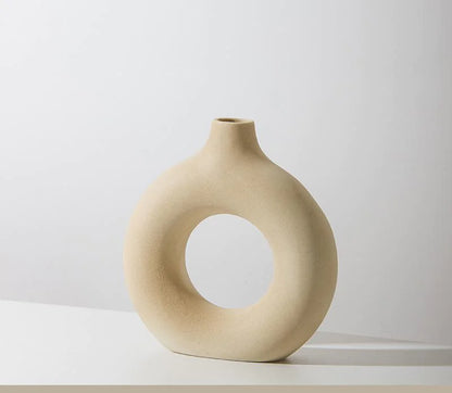 Beige ceramic vase with a circular hole on a white background