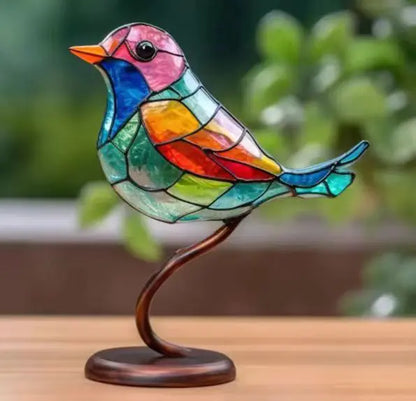 Colorful stained glass bird sculpture on a wooden surface with a blurred green background