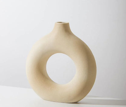 Beige ceramic vase with circular design on a white background