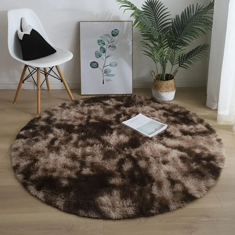 Round brown rug on a wooden floor with a chair, plant, and artwork in the background.