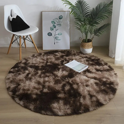 Round brown rug on a wooden floor with a chair, plant, and artwork in the background.